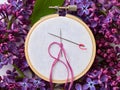 Embroidery hoop with needle and pink thread surrounded by lilac flowers Royalty Free Stock Photo