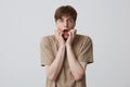 Closeup of stunned scared young man with opened mouth wears beige t shirt standing and shouting  over white background Royalty Free Stock Photo