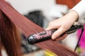 Closeup of stylist hands with iron straightening woman hair