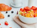 Closeup summer breakfast with bowl of healthy fresh fruit salad, coffee, milk and croissants Royalty Free Stock Photo