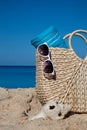 Closeup of summer straw bag with blue towel and sunglasses on a Royalty Free Stock Photo