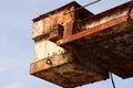 Closeup of a sunlit old rusty port crane with clear sky bcakground