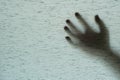 Closeup surface shadow of hand behind gray fabric curtain textured background with copy space in horror concept Royalty Free Stock Photo