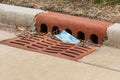 Closeup of surgical face mask discarded in storm sewer drain grate. Royalty Free Stock Photo