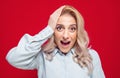 Closeup surprised face young woman, isolated on red background. Amazing blond girl. Head shot of a amazed woman