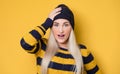 Closeup surprised face young woman, model wearing woolen cap and sweater, on yellow background. Amazing european woman.
