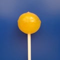 Sweet yellow lollipop over blue background.
