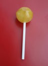 Sweet yellow lollipop over red background.