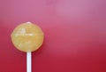 Sweet yellow lollipop over red background.