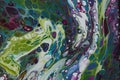 Closeup of a swirling abstract acrylic pour painting with blending greens, blues, and purples.
