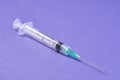 Closeup of a syringe needle with the vaccine against a purple background - COVID-19