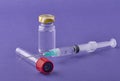 Closeup of a syringe needle with the vaccine ampoules on a purple surface - COVID-19