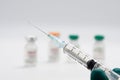 Closeup syringe with vaccine against covid-19 on blurred background of vial with coronavirus vaccine.