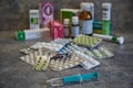 Closeup of a syringe and various pills in the background. Vaccine in a syringe. Collection of various pills and drugs