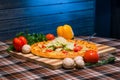 Closeup of table for lunch, pizza, vegetables, yellow and red peppers, mushrooms on wooden board