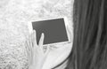 Closeup tablet computer on asian woman hand on blurred gray carpet floor textured background with copy space in black and white to Royalty Free Stock Photo