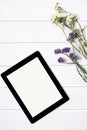 Closeup tablet with a empty blank screen monitor with a bouquet of flowers on white table background with natural wood vintage