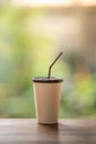 Closeup of take away paper cup of iced coffee on wooden table with green nature background Royalty Free Stock Photo