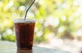 Closeup of take away plastic cup of iced black coffee Americano on wooden table with green nature background Royalty Free Stock Photo