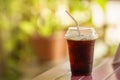 Closeup of takeaway plastic cup of iced black coffee Americano on wooden table with green nature background Royalty Free Stock Photo