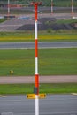 A closeup of a tall red and white striped lamppost with airplane parking spot indicators