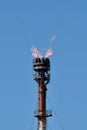 Oil Refinery Equipment with Orange Flames, against Pure Blue Sky