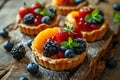 closeup of tartlets with fresh different berries, bakery dessert with sweet strawberry, blueberry, blackberry and mint leaves on