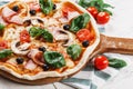 .CLOSEUP Tasty Italian Hot Pizza on white wooden table with mushrooms, basil, tomato, olives and cheese. Look as Prosciutto, Royalty Free Stock Photo