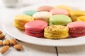 Closeup of tasty multicolored macaroons on a white porcelain plate. Sweet breakfast with delicious almond meringue cookies. Royalty Free Stock Photo