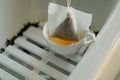 closeup of tea bag steeping in cup on bathtub tray