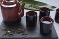 Closeup of tea set and hot green tea.Tea cups, pot, black mat, green leaf on the grey table Royalty Free Stock Photo