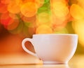 Closeup of teacup isolated on a colourful and vibrant bokeh background. Concept of one white coffee cup on a table in a Royalty Free Stock Photo