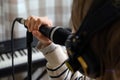 Closeup of teenager recording music in home studio. Girl with headphones and microphone recording song