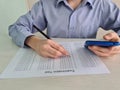 Closeup of teenager sitting at desk holding phone in her hand and taking exam test Royalty Free Stock Photo