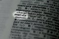 closeup of term and definition of mercy printed and highlighted in dictionary on white page. Royalty Free Stock Photo