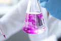 Closeup of test tube with pink liquid in hand of scientist