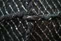 A closeup of the texture and pattern on black mesh fabric, with white metal wire threads that form an intricate grid against a so