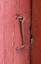 Closeup of textured red door with a rusty metal hook. Bright wooden doorway and doorframe aged with cracked patterns Royalty Free Stock Photo