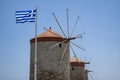 Closeup of the Three Ancient Windmills and the Greek Flag Against the Blue Sky on the Harbor of Rhodes Royalty Free Stock Photo