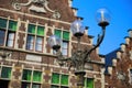 Closeup of three armed old street lamp with typical belgian stepped gable house facade background against blue sky