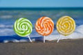 Closeup of three different lollipops on a beach surrounded by the sea - great for wallpapers Royalty Free Stock Photo