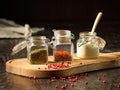 A closeup of three jars of spices and white sauce on a wooden cutting board