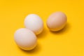 Closeup of three natural color ecological eggs on yellow background randomly alined
