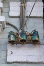 Three old-fashioned out-of-date ceramic insulators for a hand-made electric line mounted on an old damaged wall