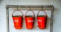 Closeup of three red old fire buckets hanging from a metal pipe Royalty Free Stock Photo