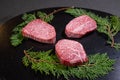 Closeup of three slices of raw wagyu beef on evergreen leaves on a board