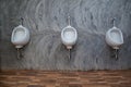 Closeup of three white urinals in men`s bathroom design of white