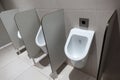 Closeup of three white urinals in men`s bathroom design of white ceramic urinals for men in toilet room, Loft wall Royalty Free Stock Photo