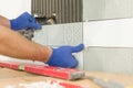 Closeup of tiler hand laying ceramic tile on wall in kitchen, renovation, repair, construction Royalty Free Stock Photo