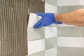 Closeup of tiler hand laying ceramic tile on wall in kitchen, renovation, repair, construction